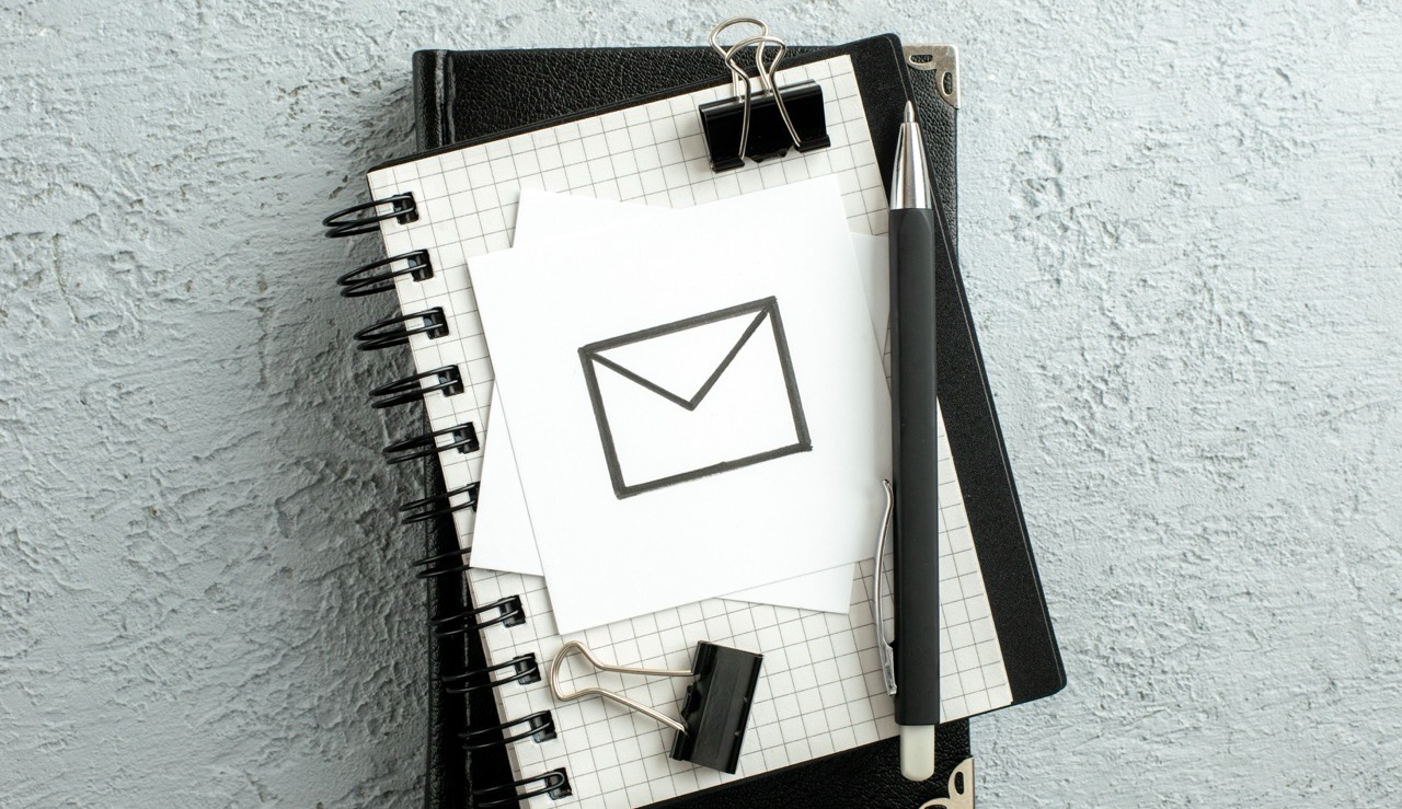 Top view of message drawing on white sheet pen on spiral notebook and book on gray sand background Top view of message drawing on white sheet pen on spiral notebook and book on gray sand background